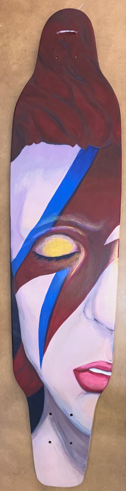 Acrylic painting on a skate deck of a Bowie-inspired face with a blue lightning bolt and a gold-rimmed eye